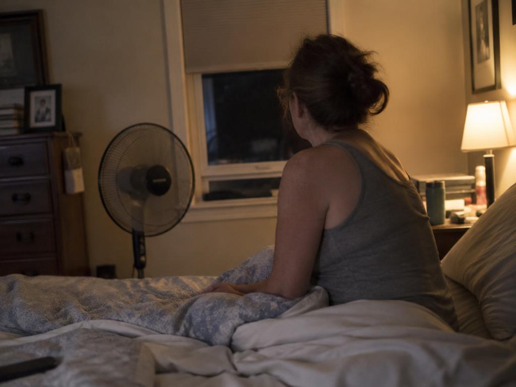 Woman in her forties sitting on the edge of her bed early in the morning