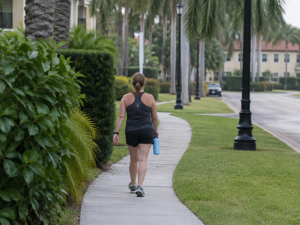 Adult walking outdoors on a tree-lined South Florida path